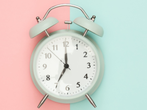 A clock on a pink and teal background.