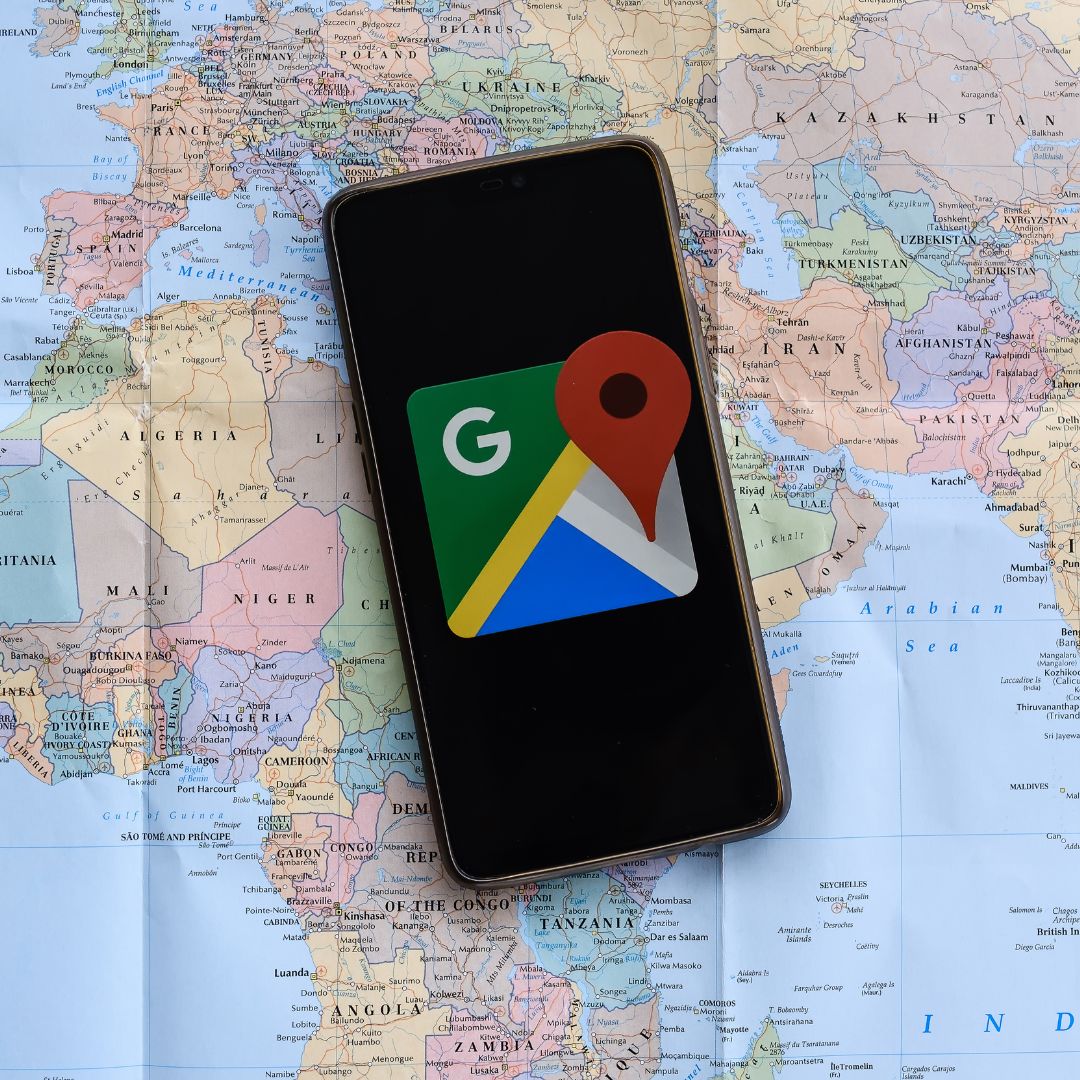 Phone with a Google Maps graphic on it on top of a real map.